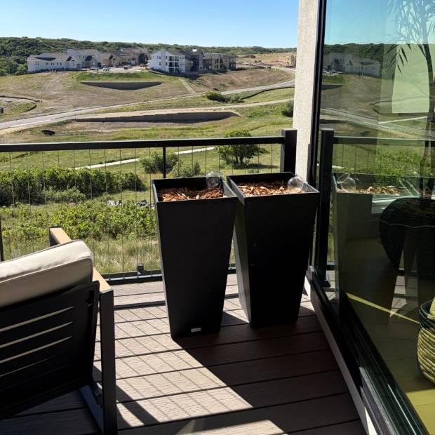 Empty tapered planters on a balcony with a prairie view